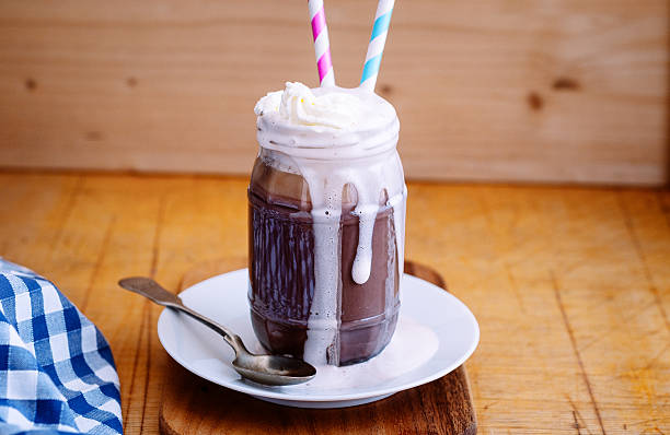 Hot chocolate in glass jar with cream and straws